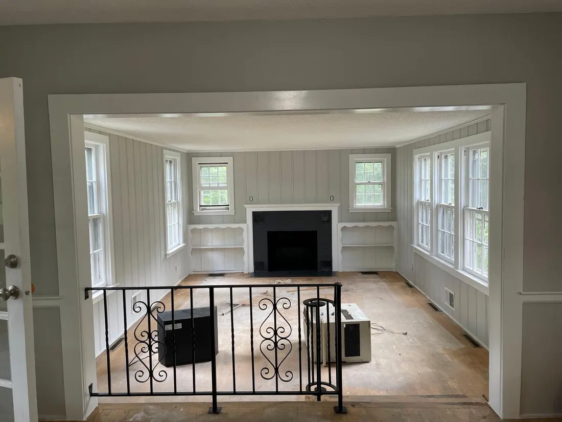 Interior room freshly painted in soft sage green with crisp white trim and a refinished fireplace