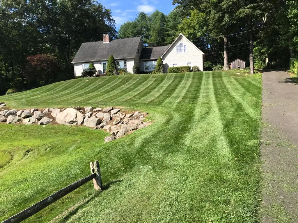 Fresh mulch beds and lush plantings bordering a striped Connecticut lawn